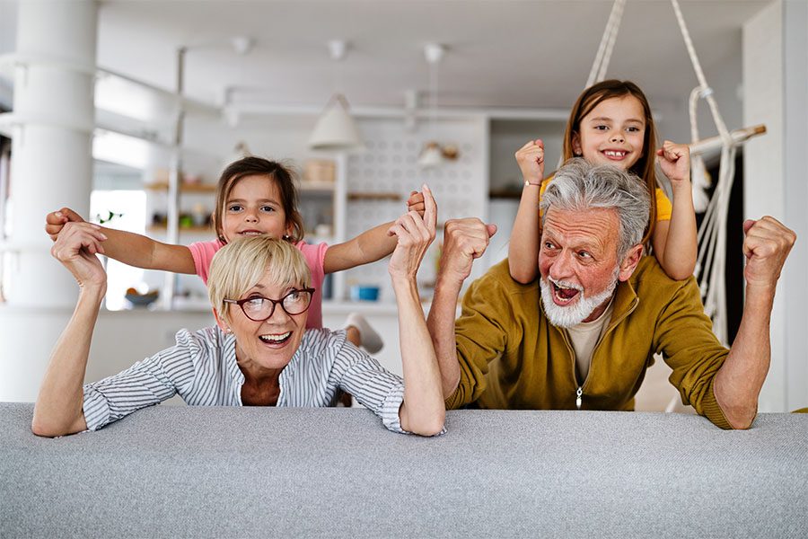 Client Center - Portrait of Cheerful Grandparents Having Fun Playing with Their Granddaughters at Home