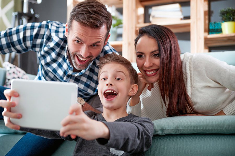 Home Insurance Quote - Happy Family on the Sofa of Their New Home Taking Selfie Using a Tablet